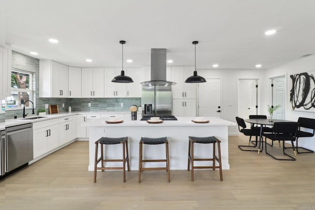 3243 Carolyn Cir, Oceanside, CA 92054 - kitchen with appliances with stainless steel finishes, island exhaust hood, a sink, a breakfast bar area, and light countertops