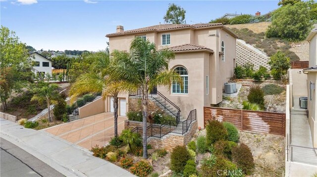 2421 N Feather Hill Dr, Orange, CA 92867 - mediterranean / spanish house featuring stucco siding, stairway, a chimney, and cooling unit