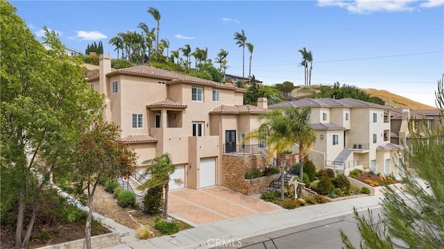 2421 N Feather Hill Dr, Orange, CA 92867 - mediterranean / spanish house featuring driveway, stucco siding, a chimney, and a tiled roof