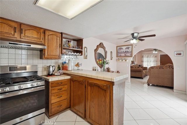 9637 San Carlos Ave, South Gate, CA 90280 - kitchen with stainless steel gas range, under cabinet range hood, ceiling fan, a peninsula, and arched walkways