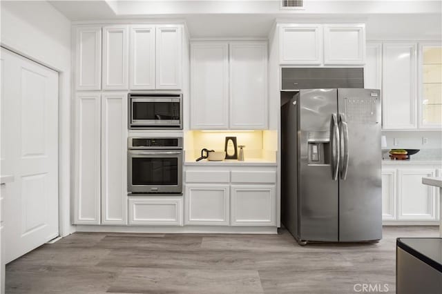 2517 Tequestra, Tustin, CA 92782 - kitchen with appliances with stainless steel finishes, white cabinets, light countertops, and light wood-style floors