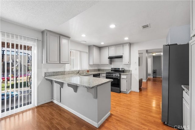 3611 Jupiter Ave, Palmdale, CA 93550 - kitchen with appliances with stainless steel finishes, a peninsula, under cabinet range hood, light wood finished floors, and recessed lighting