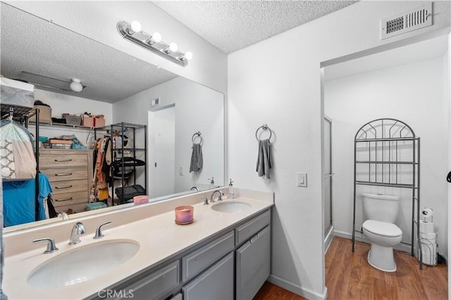 3611 Jupiter Ave, Palmdale, CA 93550 - bathroom with wood finished floors, toilet, a textured ceiling, double vanity, and a stall shower