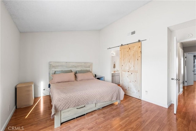 3611 Jupiter Ave, Palmdale, CA 93550 - bedroom featuring a barn door, wood finished floors, and baseboards