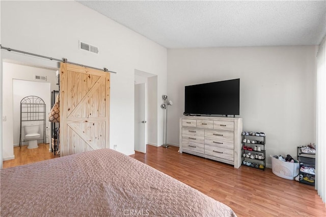 3611 Jupiter Ave, Palmdale, CA 93550 - bedroom featuring wood finished floors, a barn door, a textured ceiling, vaulted ceiling, and ensuite bath