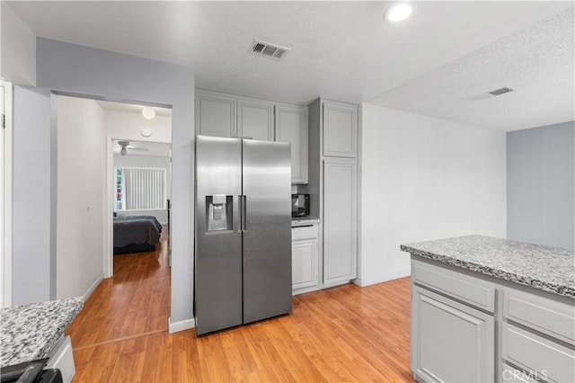 3611 Jupiter Ave, Palmdale, CA 93550 - kitchen with stainless steel fridge with ice dispenser, light wood-style floors, light stone countertops, gray cabinets, and ceiling fan