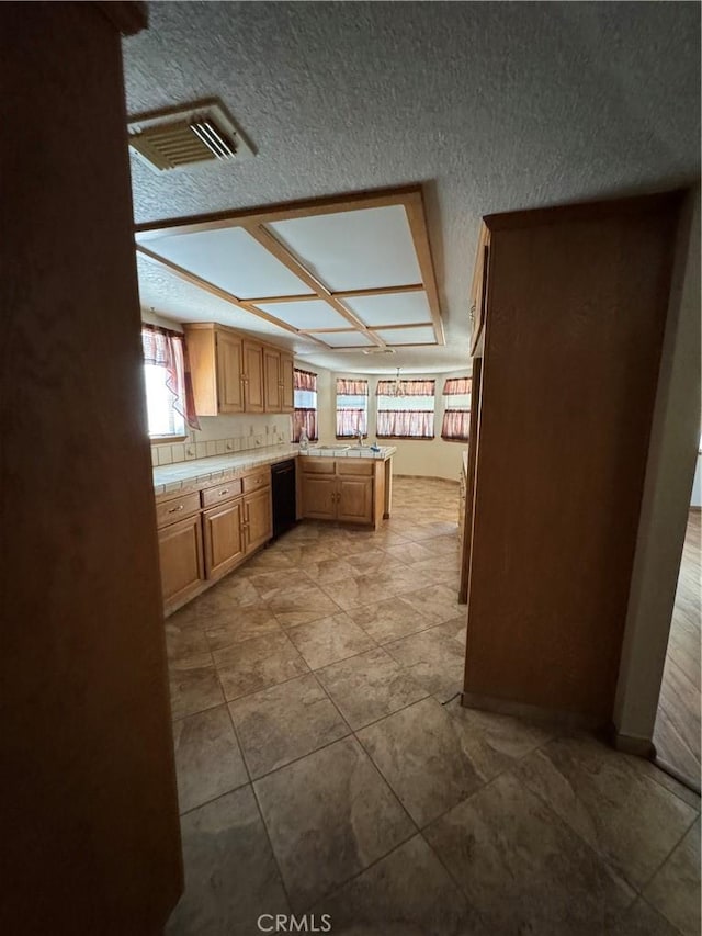 18515 Kalin Ranch Dr, Victorville, CA 92395 - kitchen with black dishwasher, a peninsula, a textured ceiling, and tile countertops