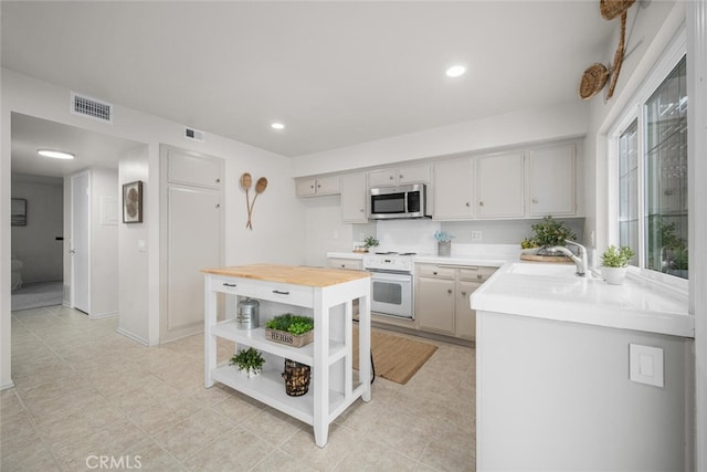 4057 Via Encinas, Cypress, CA 90630 - kitchen featuring stainless steel microwave, white range with electric stovetop, open shelves, butcher block counters, and recessed lighting