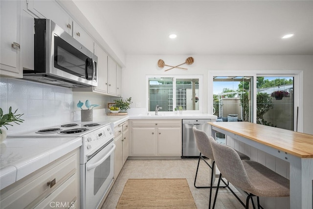 4057 Via Encinas, Cypress, CA 90630 - kitchen featuring appliances with stainless steel finishes, a kitchen breakfast bar, decorative backsplash, recessed lighting, and butcher block counters