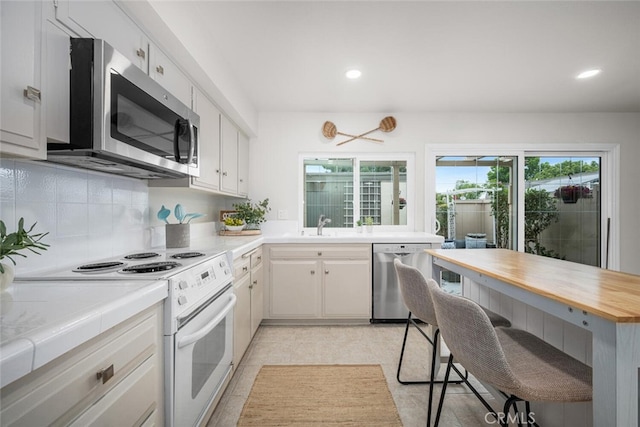 4057 Via Encinas, Cypress, CA 90630 - kitchen with appliances with stainless steel finishes, a breakfast bar area, tasteful backsplash, recessed lighting, and wooden counters