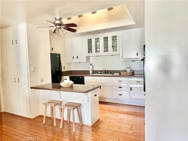 13721 El Dorado Dr Unit M3-K, Seal Beach, CA 90740 - kitchen with black appliances, a sink, dark countertops, light wood-type flooring, and a peninsula