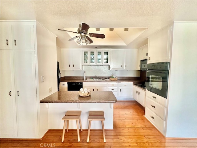 13721 El Dorado Dr Unit M3-K, Seal Beach, CA 90740 - kitchen with black appliances, a peninsula, light wood-style floors, white cabinets, and a textured ceiling