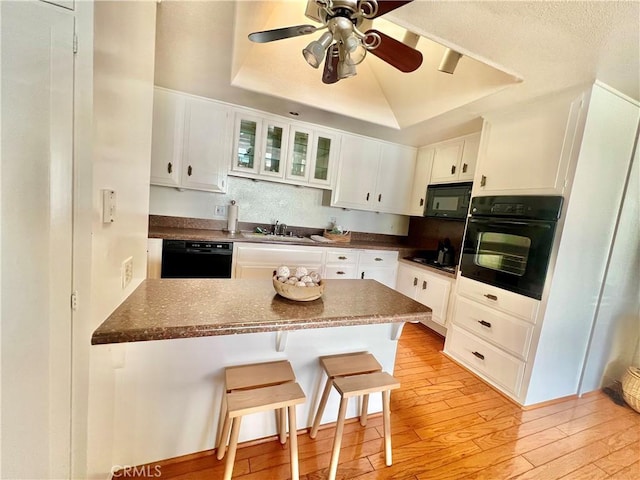 13721 El Dorado Dr Unit M3-K, Seal Beach, CA 90740 - kitchen with black appliances, a tray ceiling, white cabinets, a peninsula, and light wood-style flooring