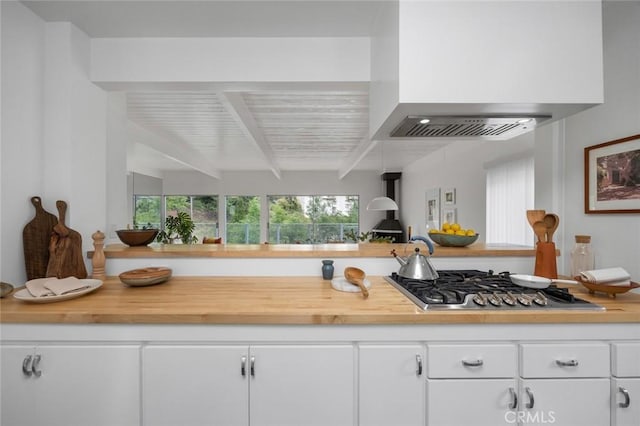 3102 Durand Dr, Los Angeles, CA 90068 - kitchen with custom range hood, stainless steel gas cooktop, beam ceiling, white cabinetry, and butcher block countertops
