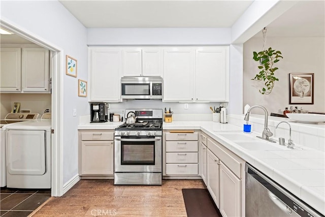 23411 Abbey Glen Pl Unit 41, Valencia, CA 91354 - kitchen featuring appliances with stainless steel finishes, washer and clothes dryer, a sink, tile counters, and white cabinets
