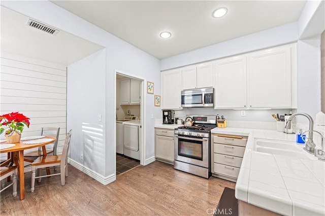 23411 Abbey Glen Pl Unit 41, Valencia, CA 91354 - kitchen featuring appliances with stainless steel finishes, tile countertops, a sink, washer and clothes dryer, and light wood-type flooring