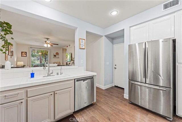 23411 Abbey Glen Pl Unit 41, Valencia, CA 91354 - kitchen featuring stainless steel appliances, tile countertops, light wood-style flooring, a ceiling fan, and baseboards