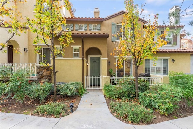 23411 Abbey Glen Pl Unit 41, Valencia, CA 91354 - mediterranean / spanish home with a tile roof, stucco siding, a fenced front yard, and a chimney