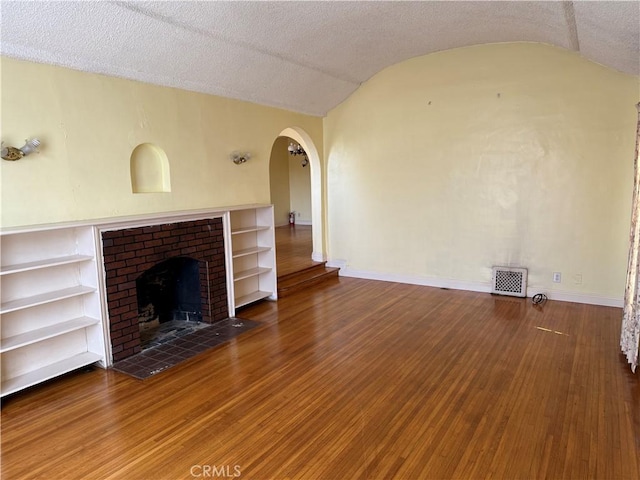 920 S Spaulding Ave S, Los Angeles, CA 90036 - unfurnished living room with arched walkways, vaulted ceiling, baseboards, a brick fireplace, and wood finished floors