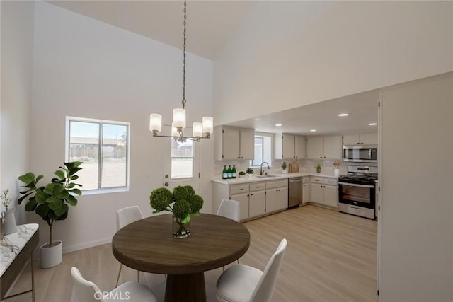 16754 Pauhaska Rd, Apple Valley, CA 92307 - dining area with light wood finished floors, a chandelier, a towering ceiling, plenty of natural light, and baseboards