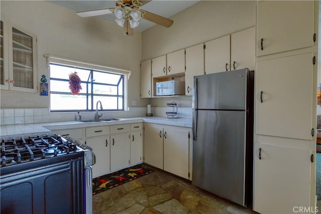 16811 Via Quedo, Desert Hot Springs, CA 92240 - kitchen with stainless steel appliances, tile counters, a sink, ceiling fan, and white cabinetry
