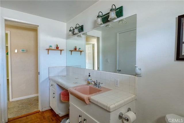 16811 Via Quedo, Desert Hot Springs, CA 92240 - bathroom featuring vanity, toilet, and decorative backsplash