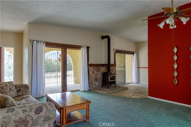 16811 Via Quedo, Desert Hot Springs, CA 92240 - living room featuring carpet floors, a textured ceiling, ceiling fan, and a wood stove