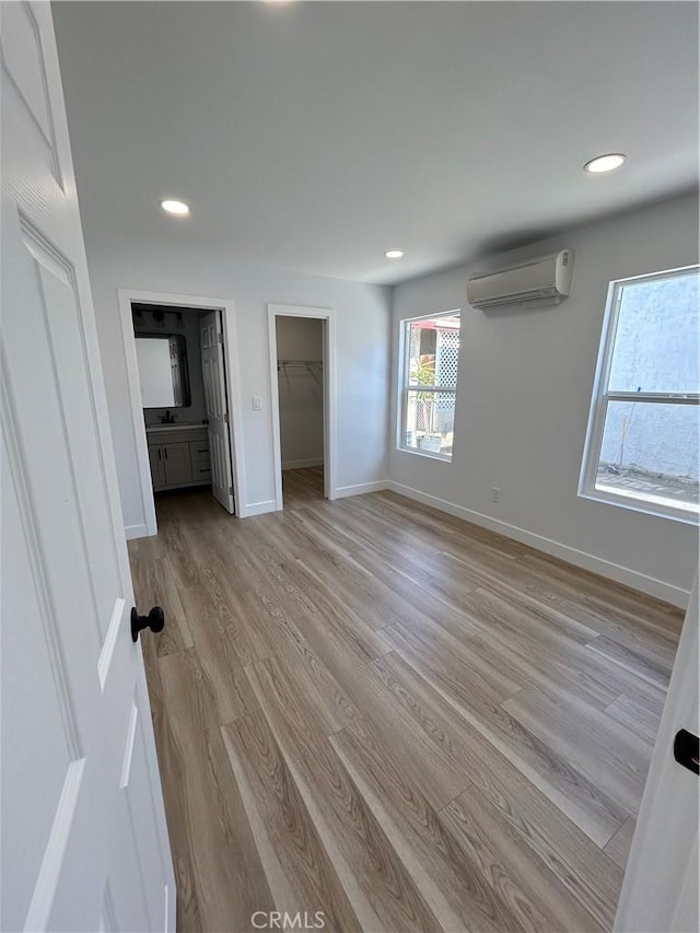 2033 W Burnett St, Long Beach, CA 90810 - unfurnished bedroom with a wall unit AC, light wood-type flooring, recessed lighting, a spacious closet, and baseboards