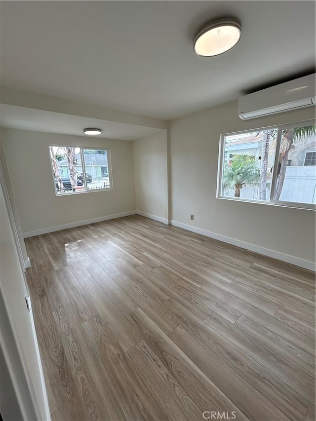 2033 W Burnett St, Long Beach, CA 90810 - spare room with an AC wall unit, light wood-style flooring, and baseboards