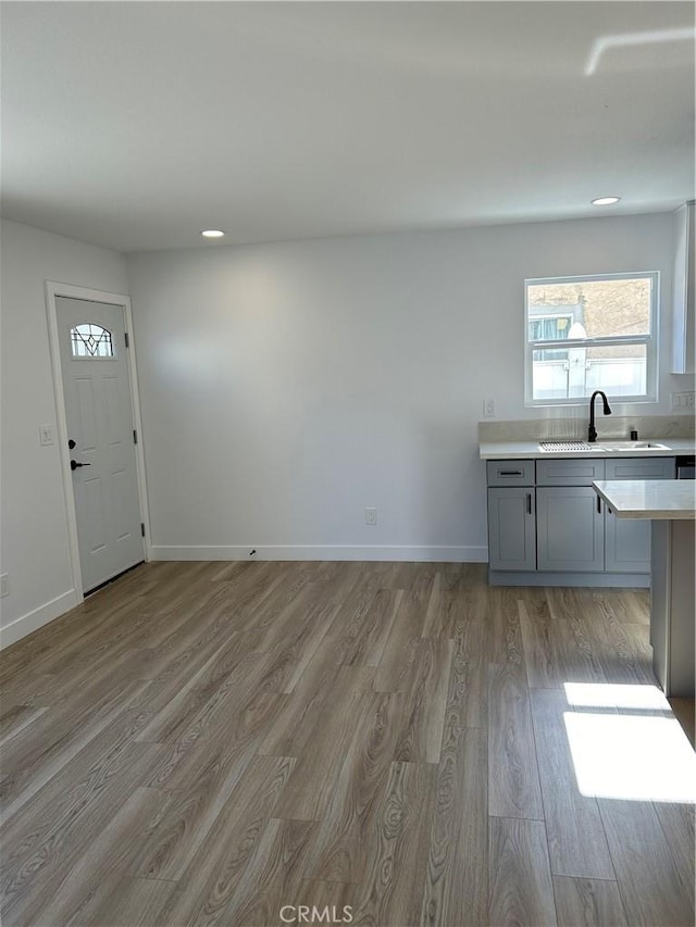 2033 W Burnett St, Long Beach, CA 90810 - kitchen featuring a sink, gray cabinetry, wood finished floors, light countertops, and baseboards