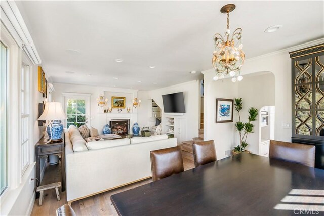 31847 8th Ave, Laguna Beach, CA 92651 - dining room featuring arched walkways, crown molding, wood finished floors, a chandelier, and a fireplace