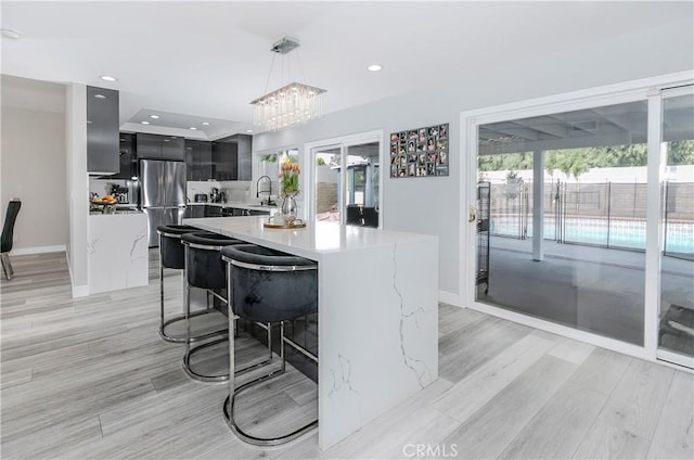 10670 Deering Ave, Chatsworth, CA 91311 - kitchen featuring modern cabinets, freestanding refrigerator, decorative light fixtures, a sink, and light wood-style floors