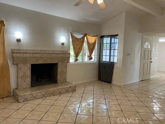 12760 Judd St, Pacoima, CA 91331 - unfurnished living room featuring a ceiling fan, light tile patterned floors, a brick fireplace, baseboards, and vaulted ceiling
