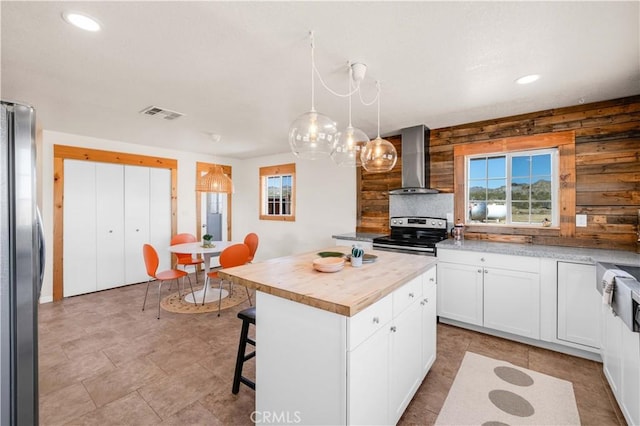 55850 Shannon Rd, Landers, CA 92285 - kitchen with wall chimney exhaust hood, stainless steel appliances, wooden counters, a breakfast bar, and white cabinets