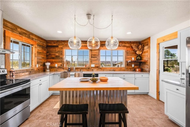55850 Shannon Rd, Landers, CA 92285 - kitchen with stainless steel range with electric cooktop, white cabinets, a breakfast bar, a kitchen island, and recessed lighting