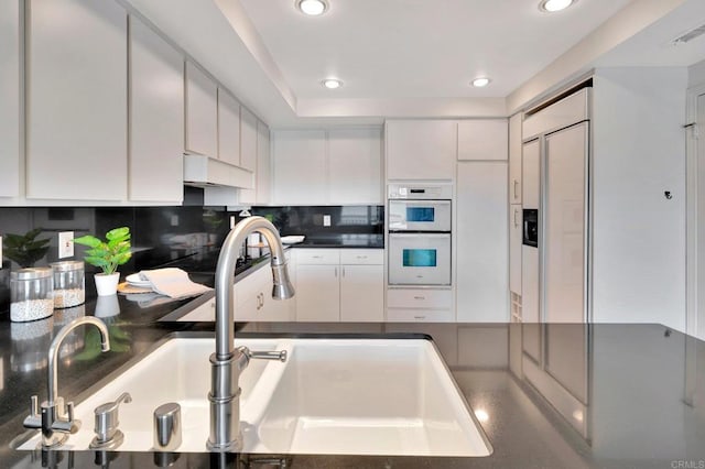 55 Jasmine Creek Dr, Corona Del Mar, CA 92625 - kitchen featuring double oven, paneled built in fridge, dark countertops, white cabinets, and tasteful backsplash