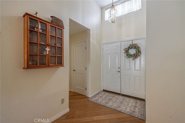5340 Gardendale Ln, Palmdale, CA 93551 - entryway with wood finished floors, a chandelier, a high ceiling, and baseboards