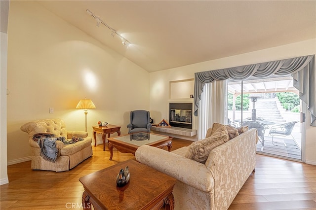 5340 Gardendale Ln, Palmdale, CA 93551 - living room featuring rail lighting, lofted ceiling, light wood-type flooring, a multi sided fireplace, and baseboards