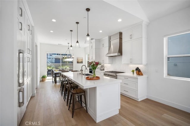 4019 Hillside Dr, San Luis Obispo, CA 93401 - kitchen featuring wall chimney range hood, stove, an island with sink, light countertops, and decorative backsplash