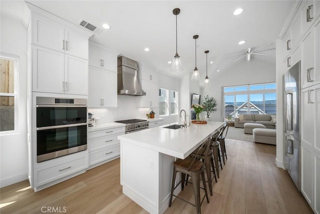 4019 Hillside Dr, San Luis Obispo, CA 93401 - kitchen with wall chimney exhaust hood, premium appliances, a ceiling fan, light wood-type flooring, and decorative backsplash