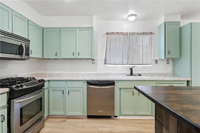 3206 4th St, Clearlake, CA 95422 - kitchen featuring stainless steel appliances, green cabinetry, a sink, and light wood-type flooring