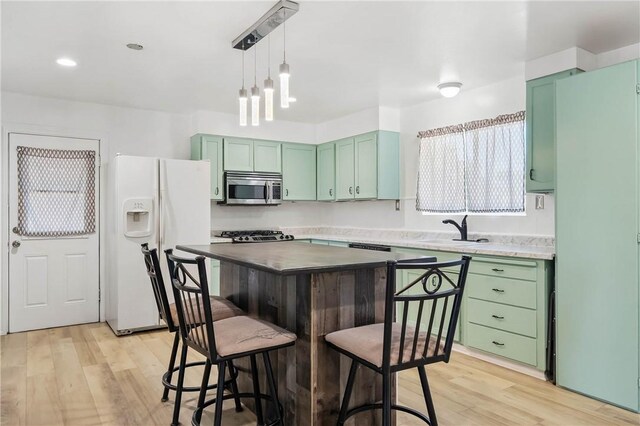 3206 4th St, Clearlake, CA 95422 - kitchen with white fridge with ice dispenser, green cabinetry, stainless steel microwave, a sink, and recessed lighting