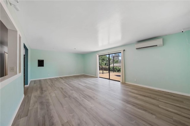 3206 4th St, Clearlake, CA 95422 - unfurnished living room with a wall mounted AC, light wood finished floors, and baseboards