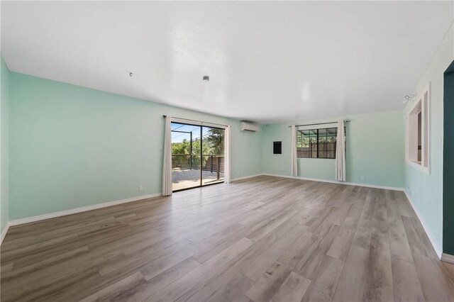 3206 4th St, Clearlake, CA 95422 - empty room featuring wood finished floors, plenty of natural light, and a wall mounted air conditioner