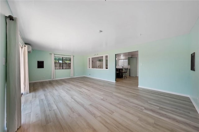 3206 4th St, Clearlake, CA 95422 - unfurnished living room with light wood-style floors, baseboards, and a wall mounted AC