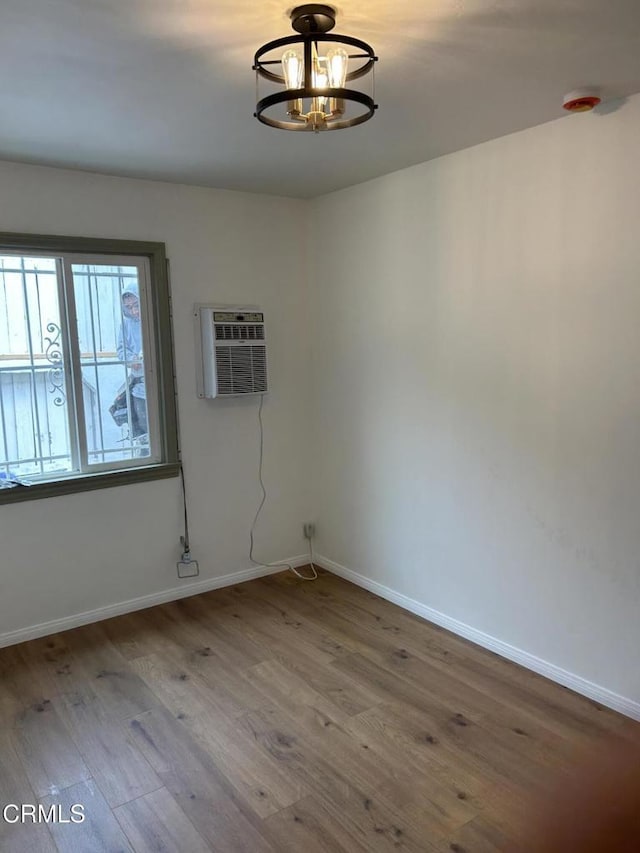 5621 Carlota Blvd, Los Angeles, CA 90042 - empty room featuring a chandelier, wood finished floors, baseboards, and an AC wall unit