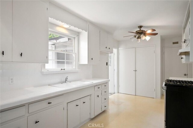 1714 N Towner St, Santa Ana, CA 92706 - kitchen featuring gas range, a ceiling fan, a sink, backsplash, and white cabinetry