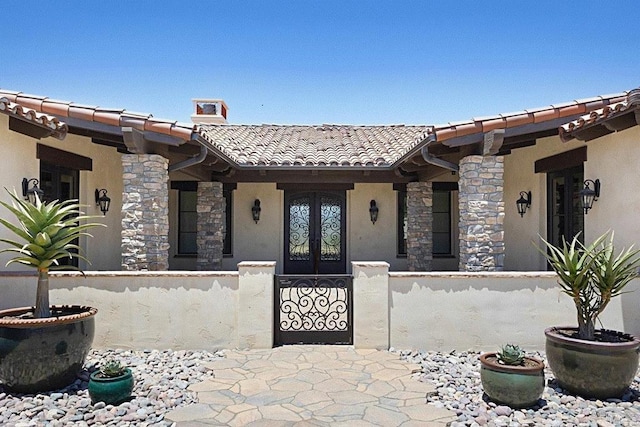 1010 Willowcreek Ln, Fallbrook, CA 92028 - view of exterior entry with a tiled roof, stone siding, stucco siding, french doors, and a chimney
