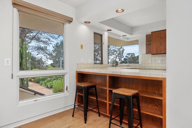 1859 Zapo St, Del Mar, CA 92014 - kitchen with a kitchen bar, light wood-style floors, tasteful backsplash, tile countertops, and recessed lighting
