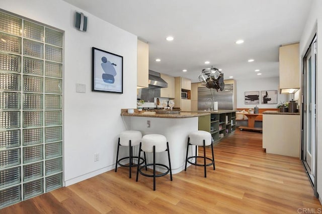 1859 Zapo St, Del Mar, CA 92014 - kitchen featuring stainless steel appliances, light wood-style floors, a breakfast bar, wall chimney range hood, and a peninsula